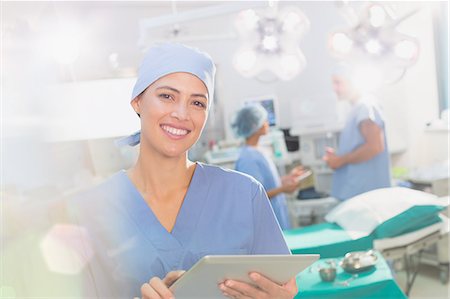 surgical gown - Portrait smiling, confident female surgeon using digital tablet in operating room Photographie de stock - Premium Libres de Droits, Code: 6124-09026401