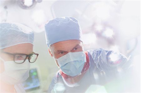 simsearch:649-07709952,k - Surgeons wearing surgical mask looking down in operating room Stock Photo - Premium Royalty-Free, Code: 6124-09026413