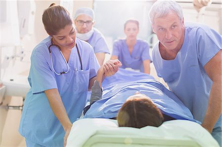 simsearch:649-07709952,k - Caring surgeons pushing patient on stretcher in hospital corridor Stock Photo - Premium Royalty-Free, Code: 6124-09026417