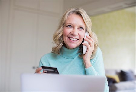simsearch:700-00688680,k - Smiling mature woman with credit card talking on telephone at laptop Stock Photo - Premium Royalty-Free, Code: 6124-09143779