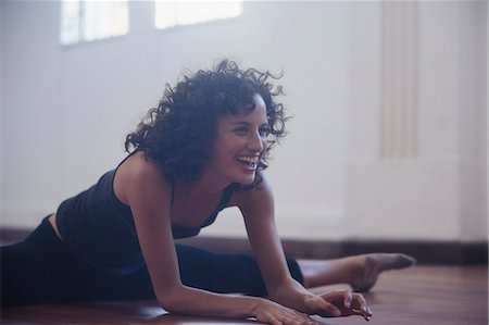 Happy, confident young female dancer stretching in dance studio Stock Photo - Premium Royalty-Free, Code: 6124-09159837