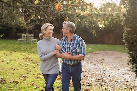 simsearch:6113-07589438,k - Happy, carefree mature couple walking arm in arm in sunny autumn backyard Stock Photo - Premium Royalty-Free, Code: 6124-09167278