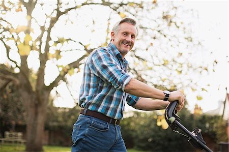 Portrait smiling senior man mowing lawn Stock Photo - Premium Royalty-Free, Code: 6124-09167218
