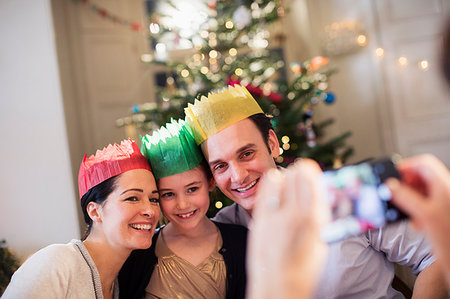 simsearch:6113-06498556,k - Happy family in paper crowns posing for photograph in Christmas living room Stock Photo - Premium Royalty-Free, Code: 6124-09177944