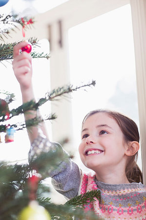 Smiling, curious girl touching ornament on Christmas tree Stock Photo - Premium Royalty-Free, Code: 6124-09177928