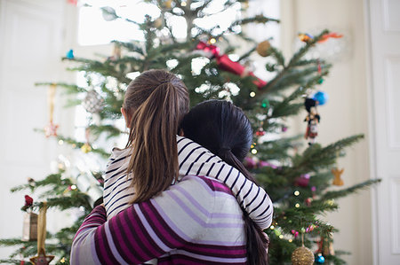 family at christmas - Affectionate mother and daughter hugging in front of Christmas tree Foto de stock - Sin royalties Premium, Código: 6124-09177930