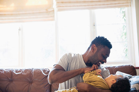 simsearch:6116-07236010,k - Playful, affectionate father and son cuddling on living room sofa Stock Photo - Premium Royalty-Free, Code: 6124-09178032