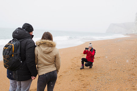 simsearch:649-08232457,k - Woman with camera phone photographing husband and daughter on snowy winter beach Stock Photo - Premium Royalty-Free, Code: 6124-09188797