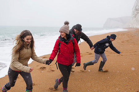 Playful family in warm clothing on snowy winter beach Stock Photo - Premium Royalty-Free, Code: 6124-09188892