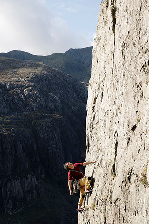 simsearch:6118-09039107,k - Male rock climber scaling large rock face, looking up Stock Photo - Premium Royalty-Free, Code: 6124-09270034