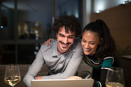 simsearch:400-05751173,k - Happy couple using laptop and drinking white wine at home at night Stock Photo - Premium Royalty-Free, Code: 6124-09239420