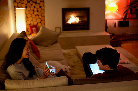 simsearch:6113-07790495,k - Couple using smart phone and digital tablet in dark living room Stock Photo - Premium Royalty-Free, Code: 6124-09239592