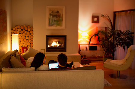 simsearch:614-02985269,k - Couple using digital tablet on living room sofa facing fireplace Stock Photo - Premium Royalty-Free, Code: 6124-09239526