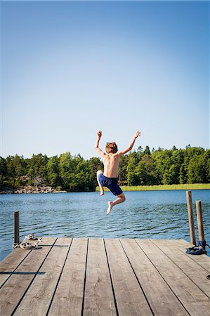 Sweden, Uppland, Runmaro, Barrskar, Rear view of boy (6-7) diving into water from jetty Stock Photo - Premium Royalty-Free, Code: 6126-08643295