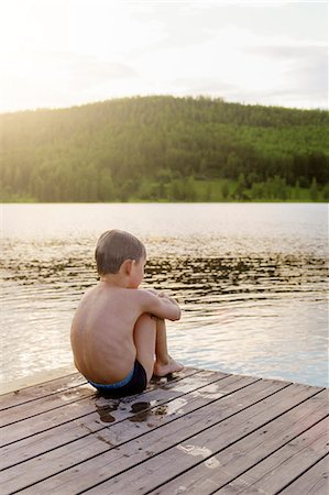 Sweden, Halsingland, Jarvso, Boy (6-7) sitting by lake Stock Photo - Premium Royalty-Free, Code: 6126-08643306
