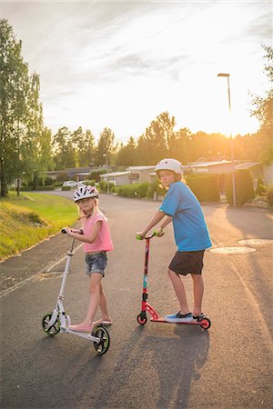 Sweden, Smaland, Anderstorp, Portrait of girl (8-9) and boy (10-11) posing with push scooters in town street Stock Photo - Premium Royalty-Free, Code: 6126-08643844