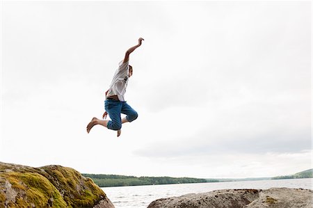 Sweden, Vastmanland, Bergslagen, Hallefors, Nygard, Teenage boy (14-15) jumping from rocks Stock Photo - Premium Royalty-Free, Code: 6126-08644000