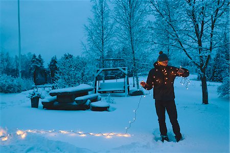 even - Finland, Jyvaskyla, Saakoski, Young man holding Christmas lights in backyard at dusk Stock Photo - Premium Royalty-Free, Code: 6126-08644870