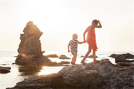 simsearch:6126-08644727,k - Sweden, Gotland, Faro, Gamle hamn, Girl (8-9) walking with brother (2-3) on coastal rocks Stock Photo - Premium Royalty-Free, Code: 6126-08658857