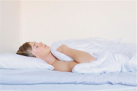 Finland, Helsinki, Portrait of young man sleeping in bed under white blanket Stock Photo - Premium Royalty-Free, Code: 6126-08659492