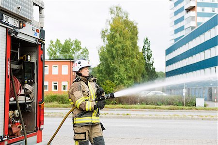 daring - Sweden, Sodermanland, Sodertalje, Female firefighter using fire hose next to truck Stock Photo - Premium Royalty-Free, Code: 6126-08635160