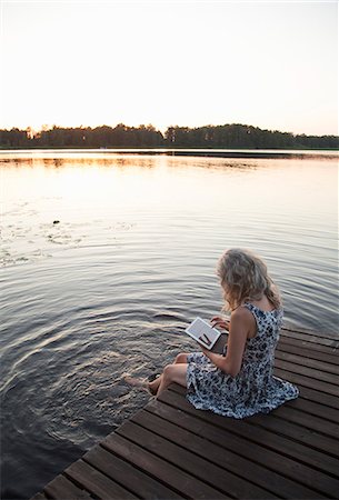 sit on dock - Sweden, Narke, Woman sitting on jetty and using digital tablet Stock Photo - Premium Royalty-Free, Code: 6126-08635191