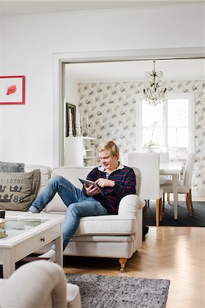 Sweden, Teenage boy (16-17) using tablet pc on sofa Foto de stock - Sin royalties Premium, Código: 6126-08635339