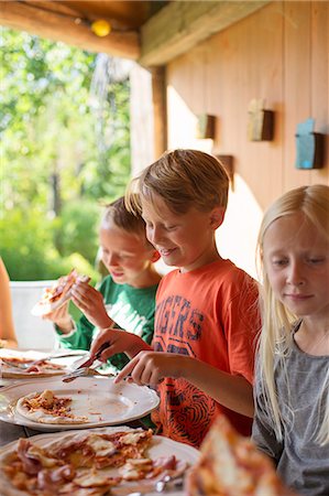 Sweden, Skane, Brothers (8-9) and sister (10-11) eating pizza at family dinner Stock Photo - Premium Royalty-Free, Code: 6126-08636075