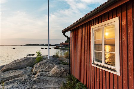 simsearch:6126-08643376,k - Sweden, Uppland, Stockholm archipelago, Nasslingen, Reflection of sun in window at sunset Foto de stock - Sin royalties Premium, Código: 6126-08636096
