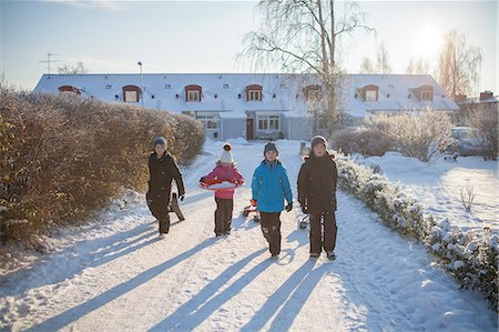 simsearch:6126-08636033,k - Sweden, Vastergotland, Lerum, Portrait of three boys (10-11) and girl (8-9) walking along snowy driveway, dragging sleds Stock Photo - Premium Royalty-Free, Code: 6126-08636017