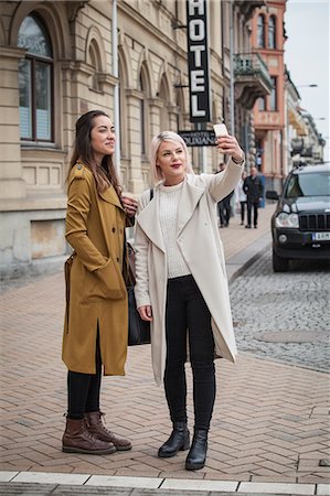Sweden, Skane, Kirstianstad, Two young women taking selfie photo on street Stock Photo - Premium Royalty-Free, Code: 6126-08781259