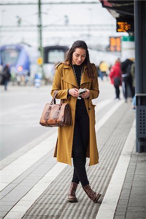 full body cell - Sweden, Skane, Kirstianstad, Young woman looking at smartphone at train station Stock Photo - Premium Royalty-Free, Code: 6126-08781263