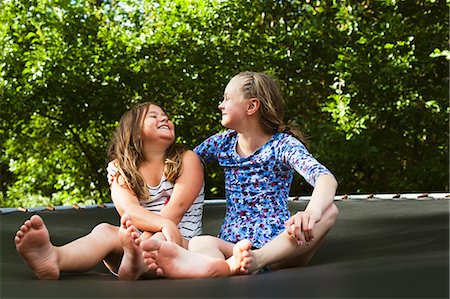 Two girls, sitting on trampoline on sunny day Stock Photo - Premium Royalty-Free, Code: 6126-09102464