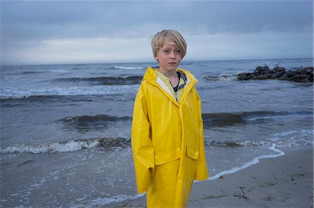 A young boy at the beach in wet weather gear Stock Photo - Premium Royalty-Free, Code: 6126-09102404