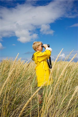 farm and boys - A young boy in wet weather gear looking through binoculars Stock Photo - Premium Royalty-Free, Code: 6126-09102409