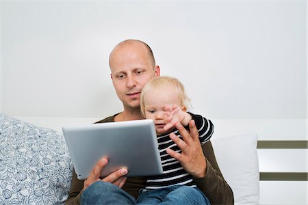 simsearch:6116-07236010,k - Stay at home dad using tablet while holding baby son Stock Photo - Premium Royalty-Free, Code: 6126-09102596