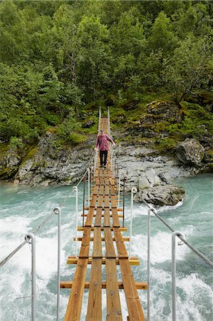 Man walking on suspension bridge over river at Jotunheimen Stock Photo - Premium Royalty-Free, Code: 6126-09102778