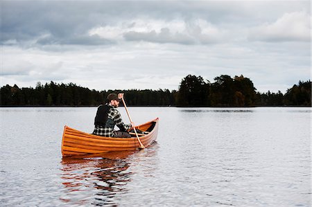 simsearch:6126-08643505,k - Mature man in boat on lake with forest on horizon Stock Photo - Premium Royalty-Free, Code: 6126-09103747