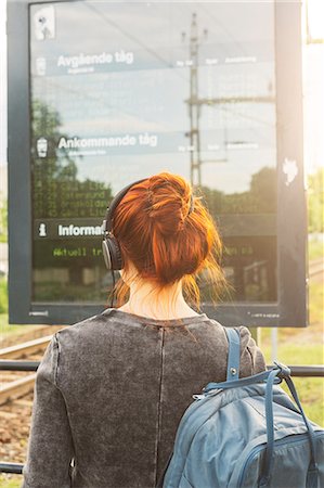 simsearch:649-08086253,k - Woman wearing headphones by train sign Stock Photo - Premium Royalty-Free, Code: 6126-09104344