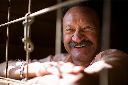 enclosure - Laughing man looking out of animal enclosure Stock Photo - Premium Royalty-Free, Code: 6128-08747602