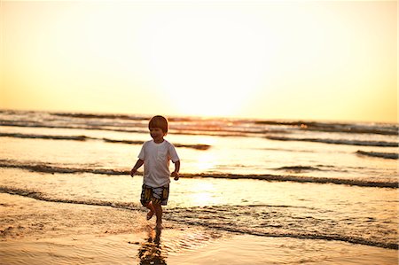 Preschool age boy running along the beach at sunset. Stock Photo - Premium Royalty-Free, Code: 6128-08747865
