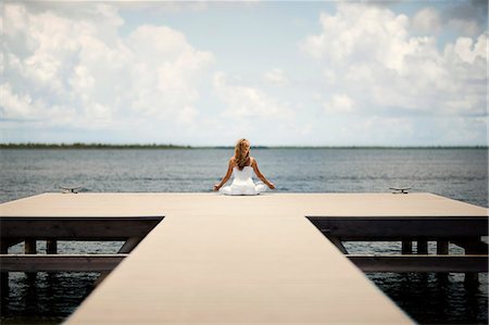 simsearch:640-03265635,k - Relaxed middle-aged woman meditating while sitting on the end of a wooden jetty. Stock Photo - Premium Royalty-Free, Code: 6128-08748005