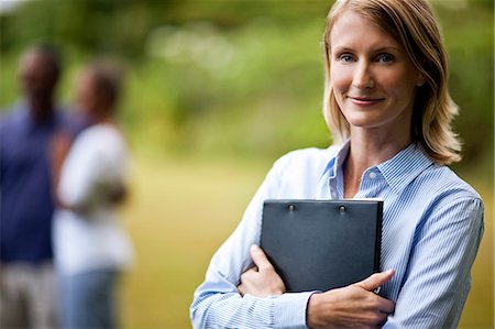 Happy real estate agent standing with satisfied couple in the background. Stock Photo - Premium Royalty-Free, Code: 6128-08748102