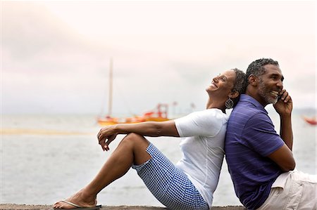 simsearch:6128-08738334,k - Happy mid-adult couple sitting together at the edge of a waterfront. Stock Photo - Premium Royalty-Free, Code: 6128-08748106
