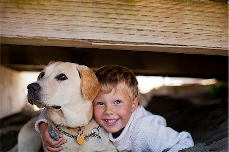 smiling lab dog - Portrait of a young boy lying under a deck with his dog. Stock Photo - Premium Royalty-Free, Code: 6128-08748135