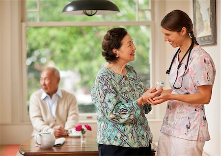 Smiling nurse giving a senior woman pill bottles. Stock Photo - Premium Royalty-Free, Code: 6128-08767049