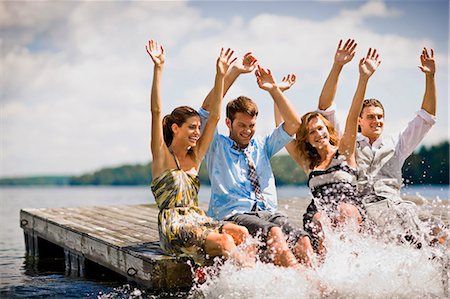 friends silly - Group of friends sitting on a jetty,  splashing in the lake with their legs. Stock Photo - Premium Royalty-Free, Code: 6128-08767089