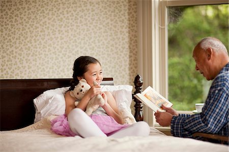 Senior man reading a story with his granddaughter. Stock Photo - Premium Royalty-Free, Code: 6128-08767034