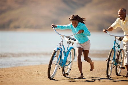 Smiling father and daughter riding their bikes on a beach. Stock Photo - Premium Royalty-Free, Code: 6128-08767238