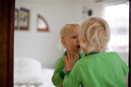 Young toddler in nappies looking at his reflection in a bedroom mirror. Stock Photo - Premium Royalty-Free, Code: 6128-08780476